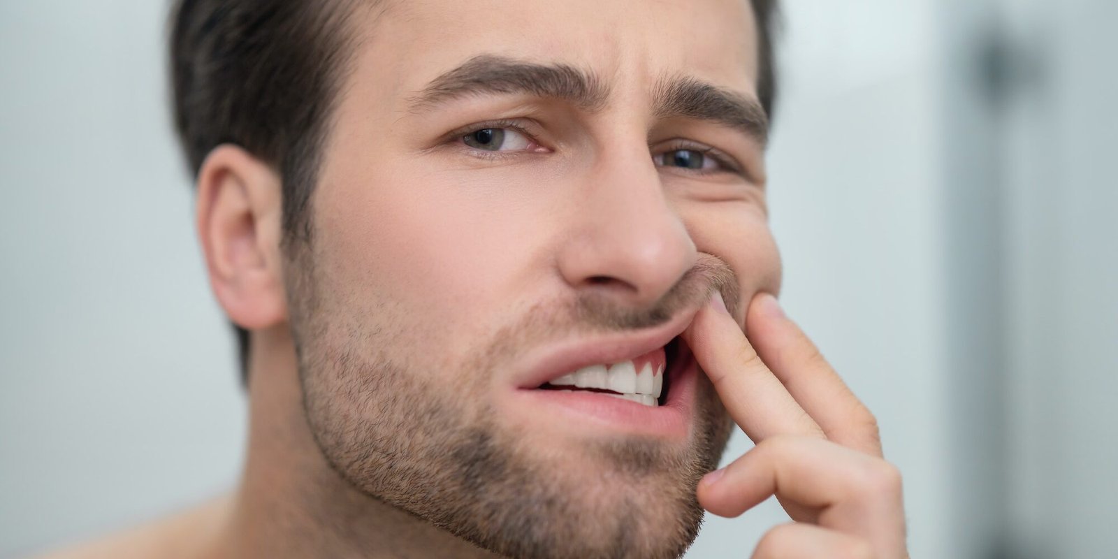 Man checking his teeth and looking disturbed
